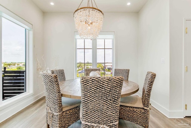 dining room featuring baseboards, light wood-style floors, and an inviting chandelier