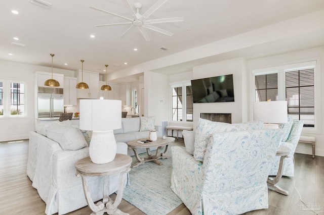 living area with recessed lighting, visible vents, a healthy amount of sunlight, and light wood finished floors