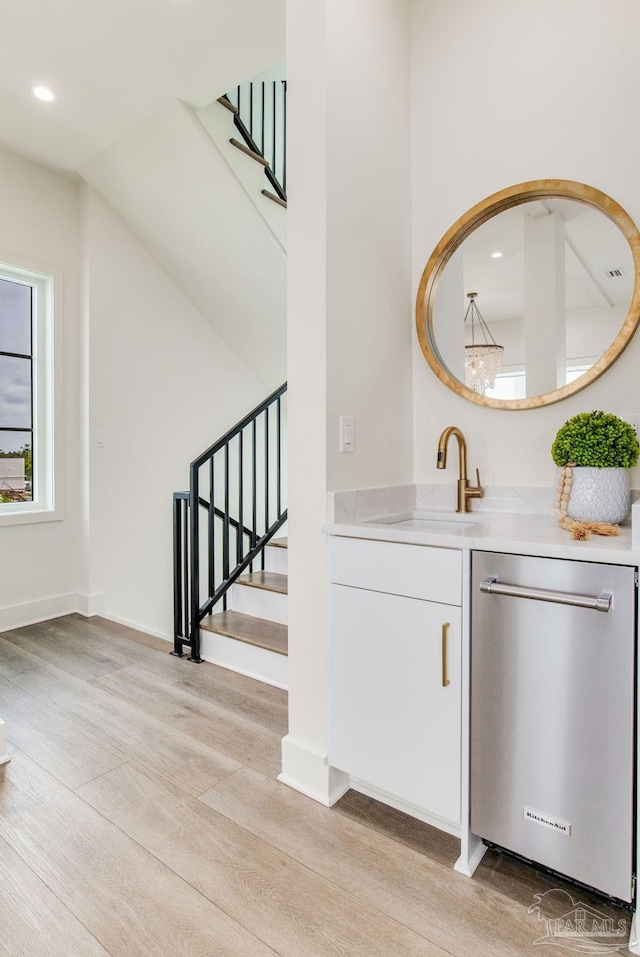 bar featuring a sink, recessed lighting, stairway, light wood-style floors, and dishwasher