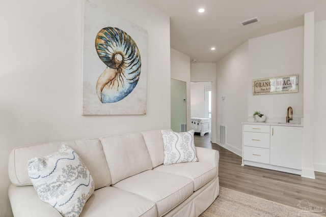 living room with recessed lighting, visible vents, light wood finished floors, and baseboards