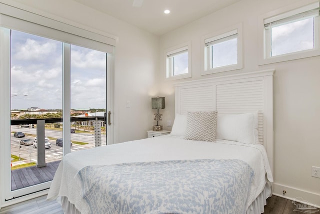 bedroom with recessed lighting, wood finished floors, baseboards, and access to outside