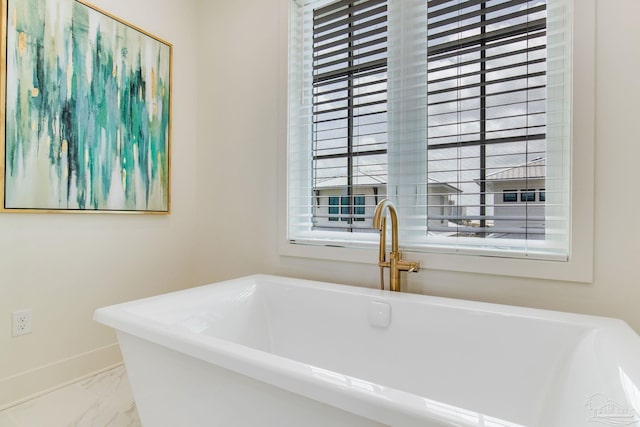 full bathroom with a soaking tub, baseboards, and marble finish floor