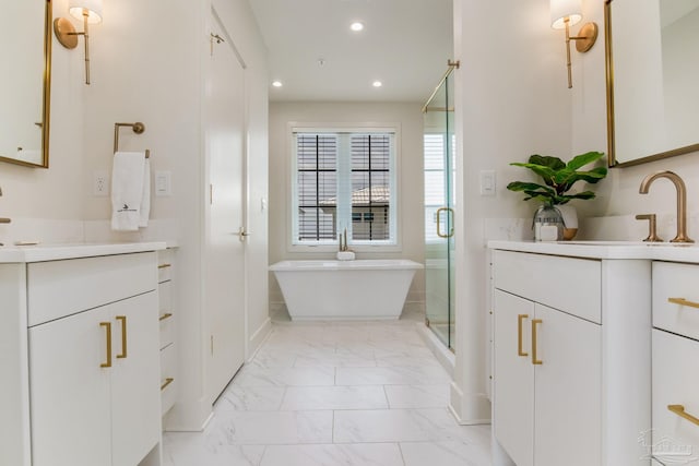 bathroom featuring a freestanding tub, two vanities, recessed lighting, a stall shower, and marble finish floor