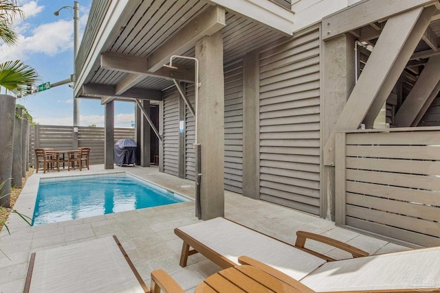 view of pool featuring glass enclosure, fence, a fenced in pool, a patio area, and a grill