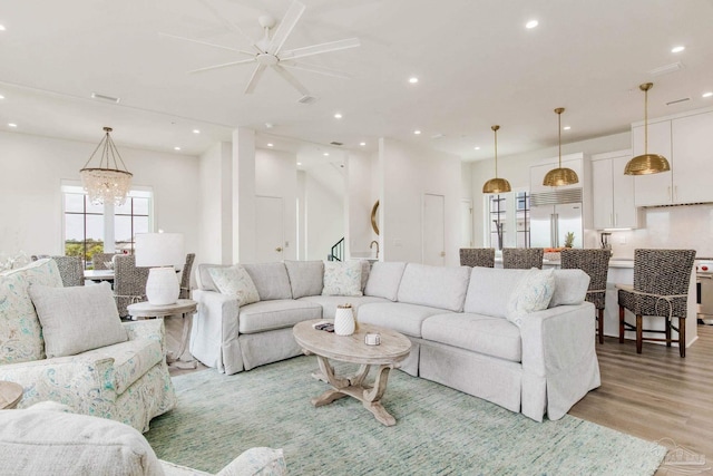 living area with recessed lighting, light wood-type flooring, and a chandelier