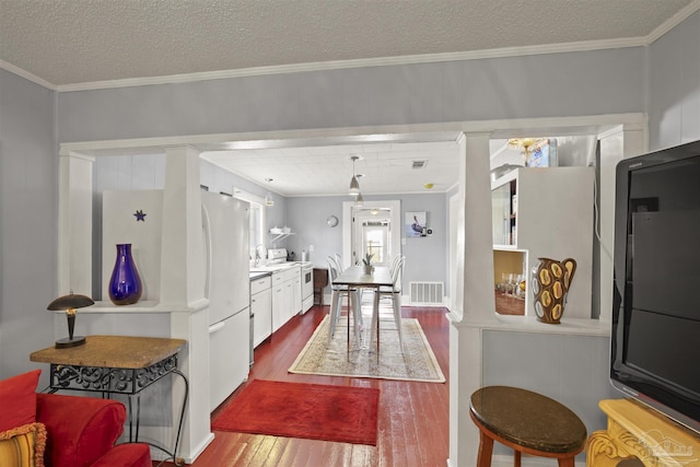 kitchen with dark wood finished floors, light countertops, visible vents, ornamental molding, and a textured ceiling