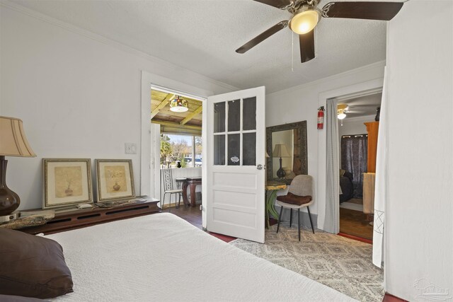 bedroom with a ceiling fan, crown molding, a textured ceiling, and wood finished floors