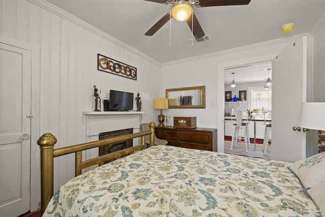 bedroom featuring a ceiling fan, a fireplace, visible vents, and crown molding