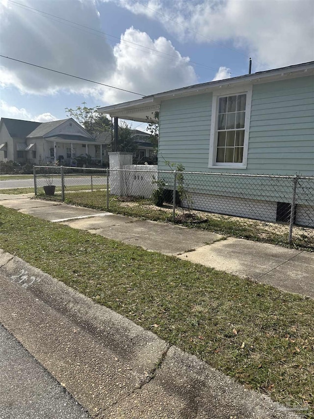 view of side of home with concrete driveway, an attached carport, and fence