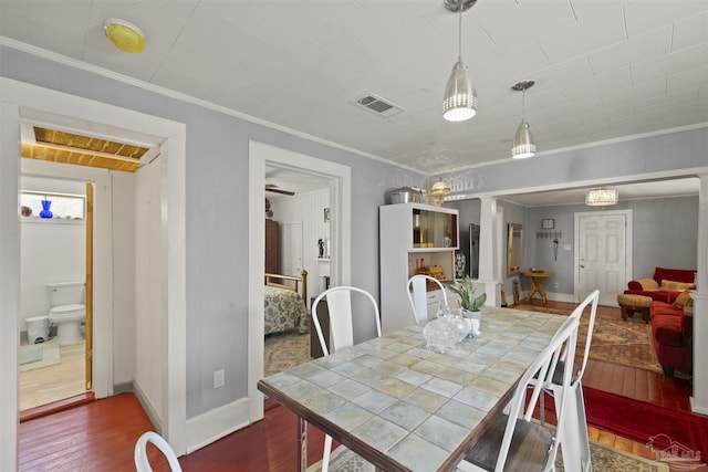 dining room featuring dark wood-style floors, visible vents, crown molding, and baseboards