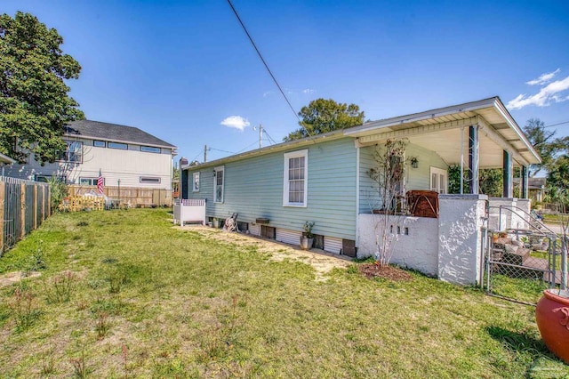 rear view of house with a lawn and a fenced backyard