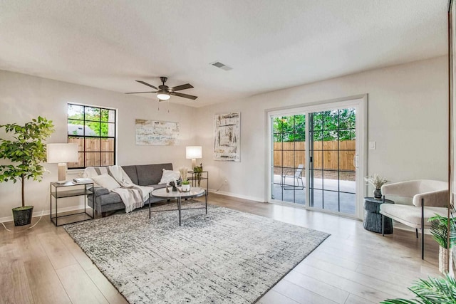 living room featuring light hardwood / wood-style floors, a textured ceiling, and ceiling fan