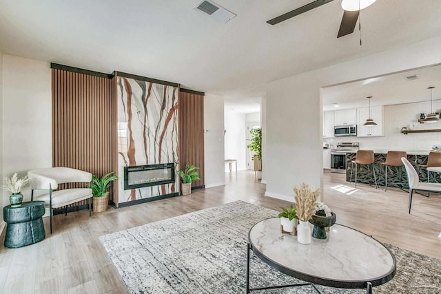 living room featuring ceiling fan, heating unit, and light hardwood / wood-style flooring