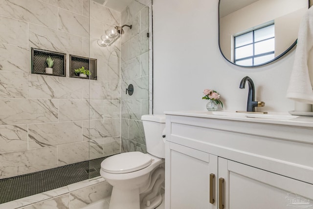 bathroom with vanity, a tile shower, and toilet