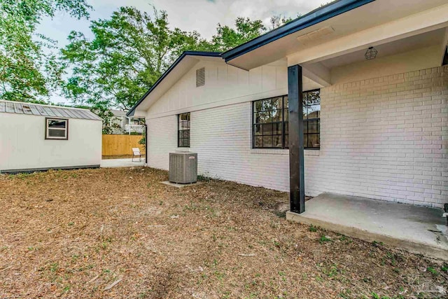 view of home's exterior featuring a patio area, central AC, and a storage unit