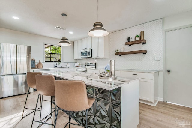 kitchen with a center island, appliances with stainless steel finishes, light hardwood / wood-style flooring, and white cabinetry