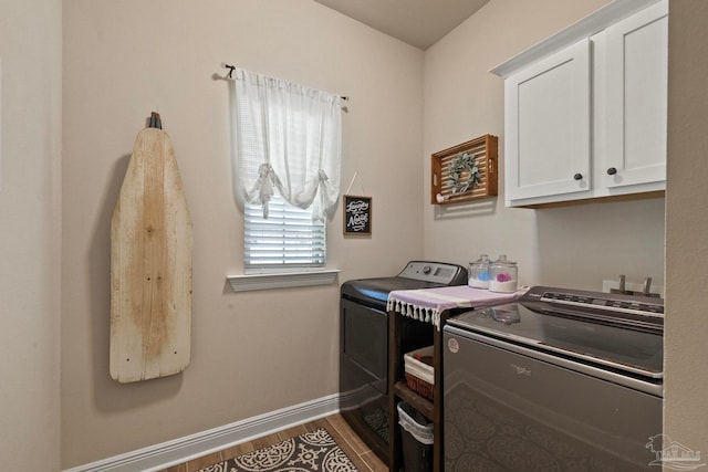 clothes washing area with washer and clothes dryer, wood-type flooring, and cabinets