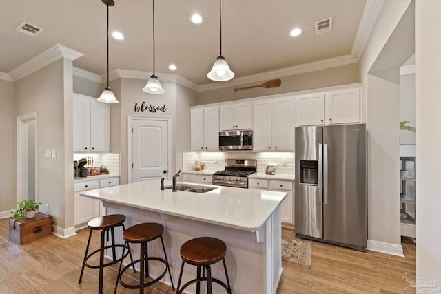 kitchen featuring white cabinetry, stainless steel appliances, light wood-type flooring, and an island with sink