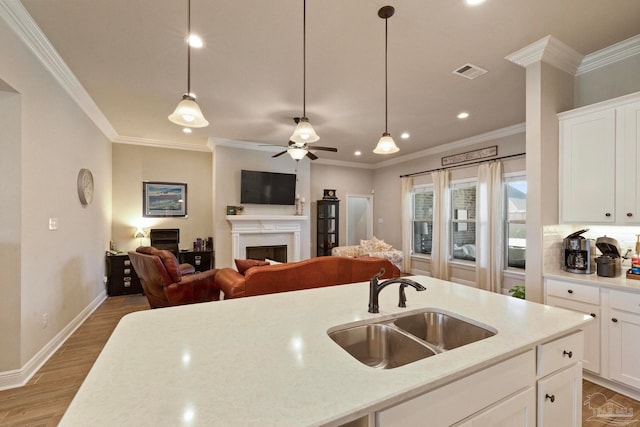 kitchen with ceiling fan, crown molding, sink, and white cabinets