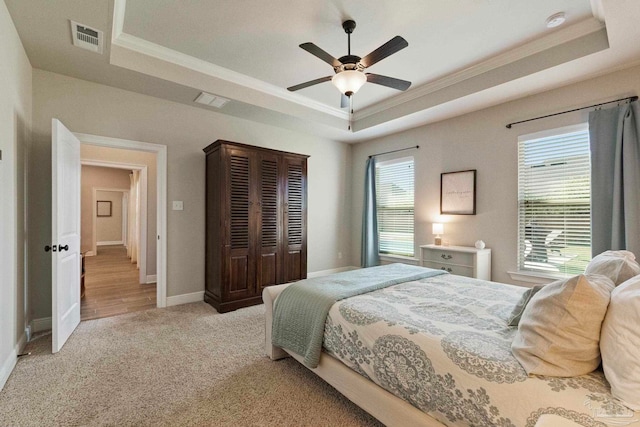 bedroom featuring ceiling fan, multiple windows, and a raised ceiling