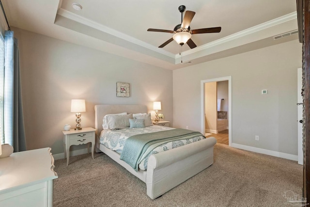 carpeted bedroom with ceiling fan, a raised ceiling, ornamental molding, and ensuite bathroom