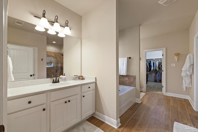 bathroom with vanity, hardwood / wood-style floors, and plus walk in shower