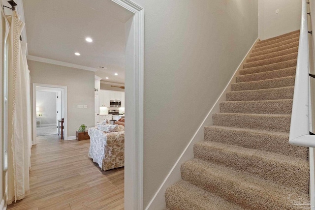 staircase with crown molding and hardwood / wood-style flooring