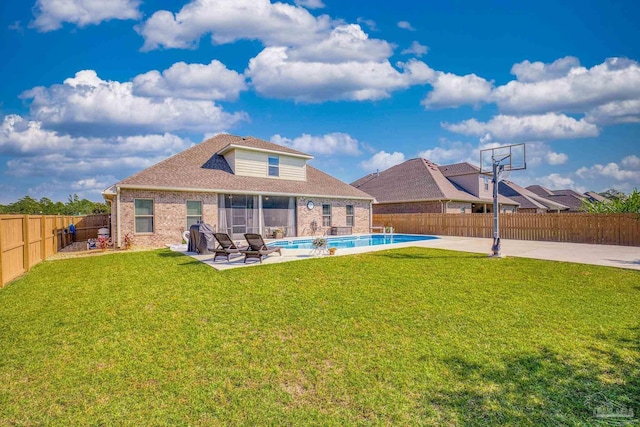 rear view of house featuring a yard, a patio, and a fenced in pool