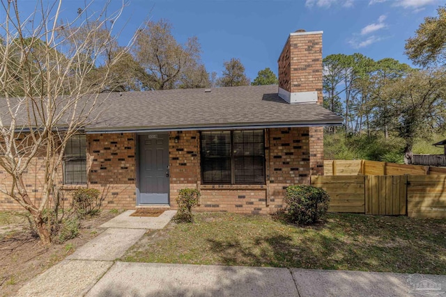 view of front of property featuring fence, brick siding, roof with shingles, and a chimney