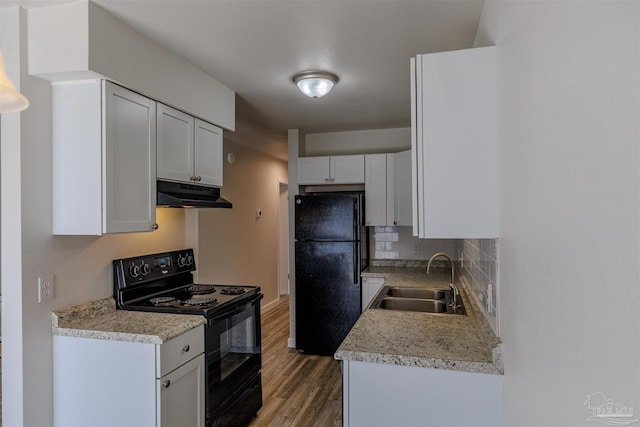 kitchen with black appliances, light countertops, under cabinet range hood, and a sink