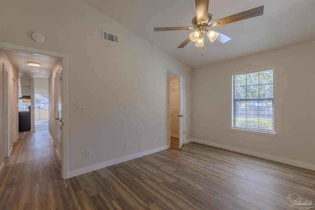 empty room featuring lofted ceiling, wood finished floors, visible vents, and baseboards