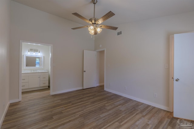 unfurnished bedroom with visible vents, baseboards, wood finished floors, ensuite bath, and a sink