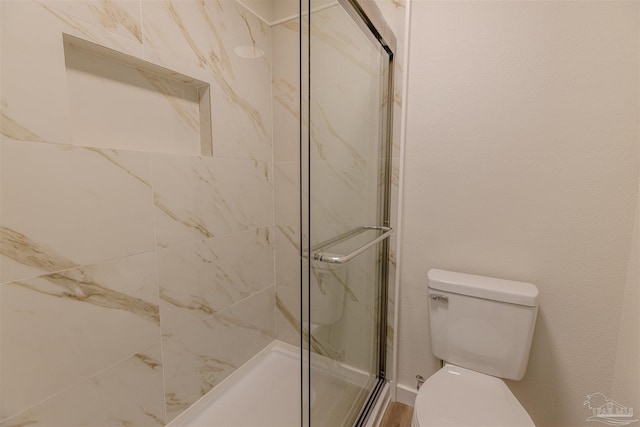 bathroom featuring a marble finish shower and toilet