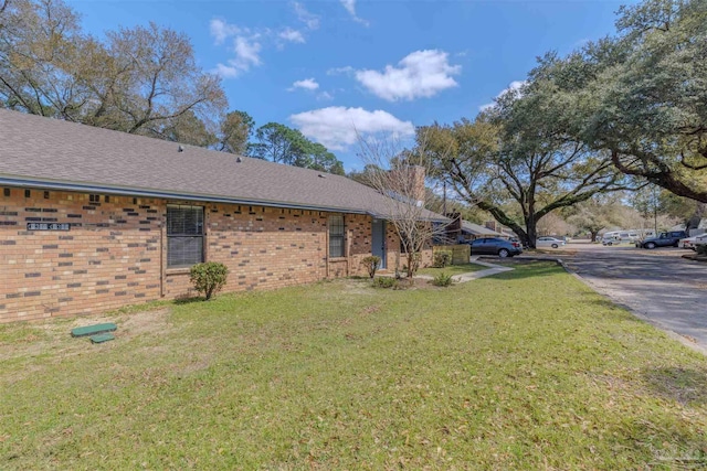 view of side of home with a yard and brick siding