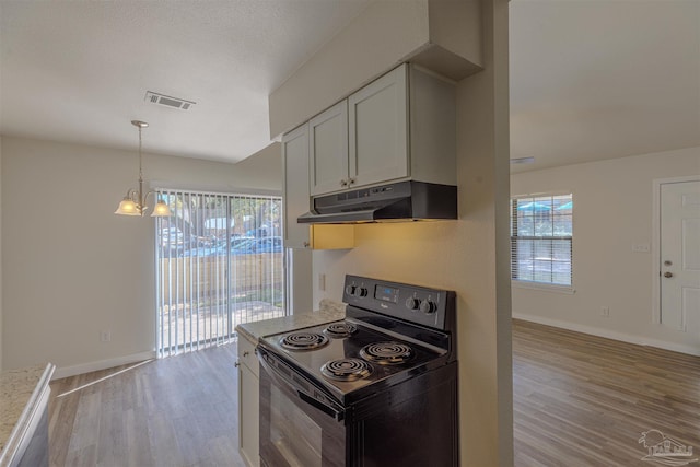 kitchen with black electric range, light wood-style floors, visible vents, and under cabinet range hood