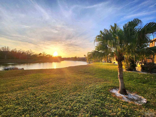 yard at dusk featuring a water view