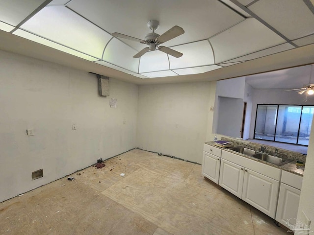 interior space with a ceiling fan, white cabinetry, and a sink