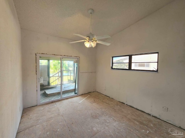 unfurnished room featuring lofted ceiling, ceiling fan, and a textured ceiling