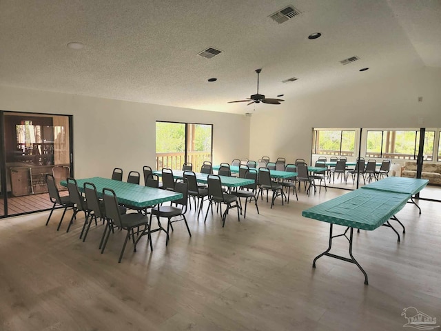 dining space with hardwood / wood-style floors, high vaulted ceiling, a textured ceiling, and ceiling fan