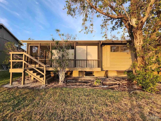 back of property featuring a sunroom and a lawn