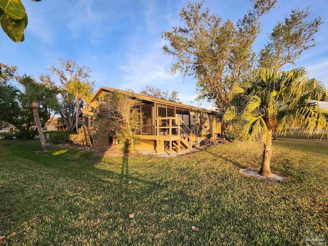 rear view of house featuring a sunroom and a lawn