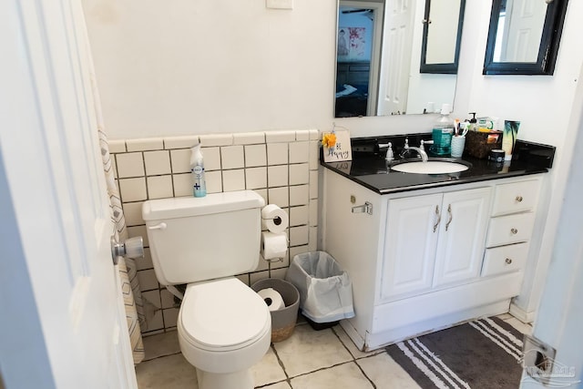 bathroom featuring tile walls, toilet, wainscoting, and vanity