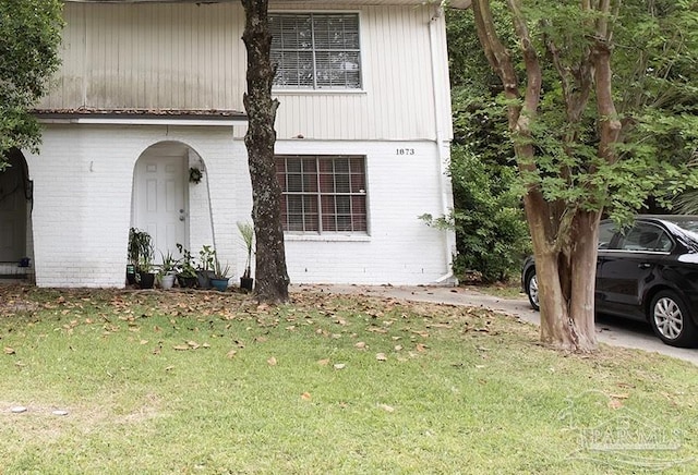 traditional-style house with brick siding and a front lawn