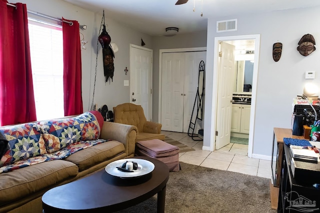 living area with light tile patterned flooring, visible vents, light carpet, a ceiling fan, and baseboards