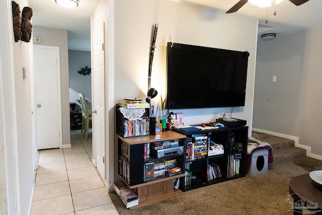 living room featuring tile patterned floors, baseboards, a ceiling fan, and stairs