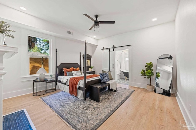 bedroom featuring visible vents, baseboards, a barn door, recessed lighting, and wood finished floors