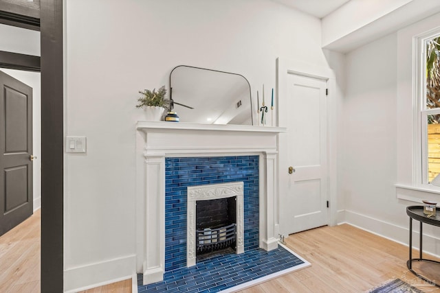 living area with wood finished floors, baseboards, and a tile fireplace