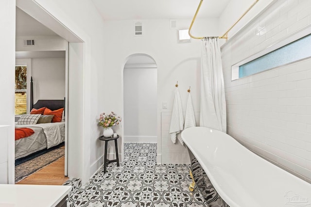 ensuite bathroom with tile patterned floors, connected bathroom, visible vents, and a freestanding bath