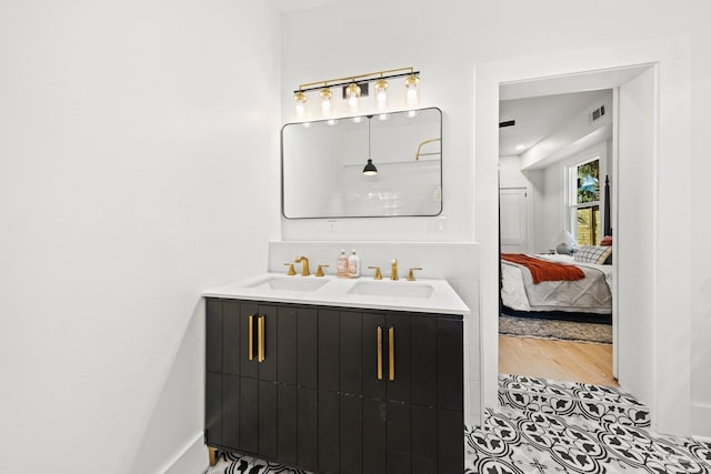 full bath with a sink, connected bathroom, visible vents, and wood finished floors