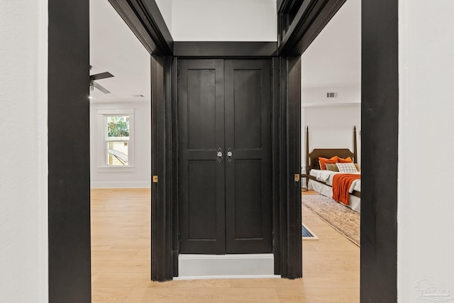 hallway featuring light wood-type flooring, baseboards, and visible vents